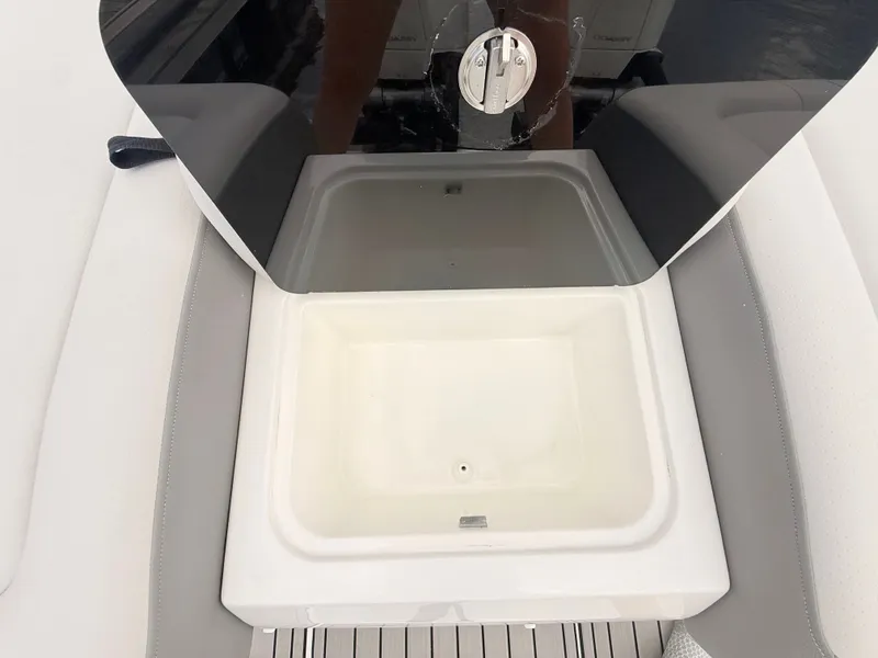 Slide: The Image of An open storage compartment on a Sea Ray SDX 290 Outboard boat, surrounded by gray upholstery. - 28
