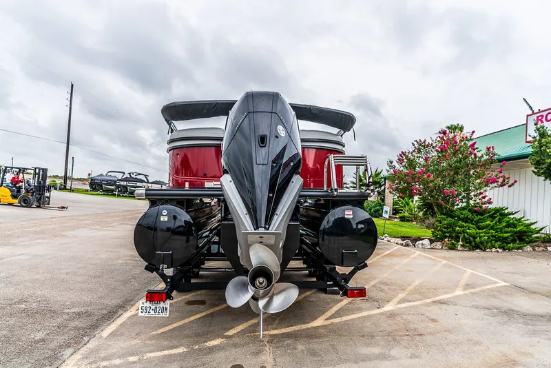 Slide: The Image of Rear view of a Regency R230 DL3 pontoon boat with an outboard motor in a parking lot. - 2