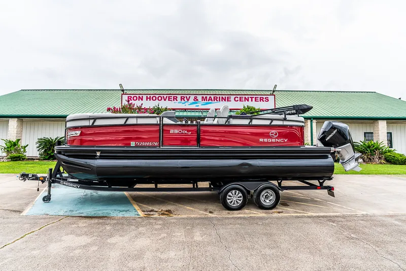 Slide: The Image of A red 2022 Regency R230 DL3 pontoon boat on a trailer in front of a building. - 3