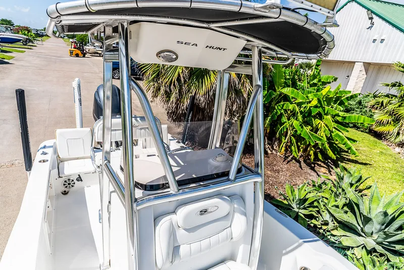 Slide: The Image of A 2016 Sea Hunt BX 20 BR boat with T-top and seating, surrounded by greenery. - 19