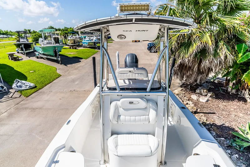 Slide: The Image of A 2016 Sea Hunt BX 20 BR boat with T-top, parked on a paved area, surrounded by palm trees. - 18