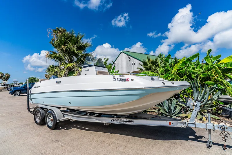 The Image of A 2016 Hurricane 21CC boat on a trailer, surrounded by palm trees and plants. - 1