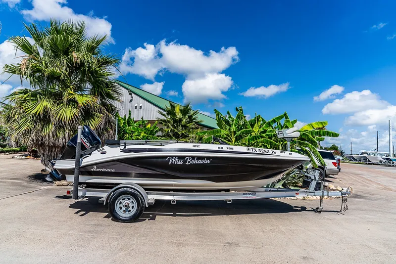 Slide: The Image of A 2020 Hurricane SS185 boat on a trailer, set against palm trees and a building. - 2