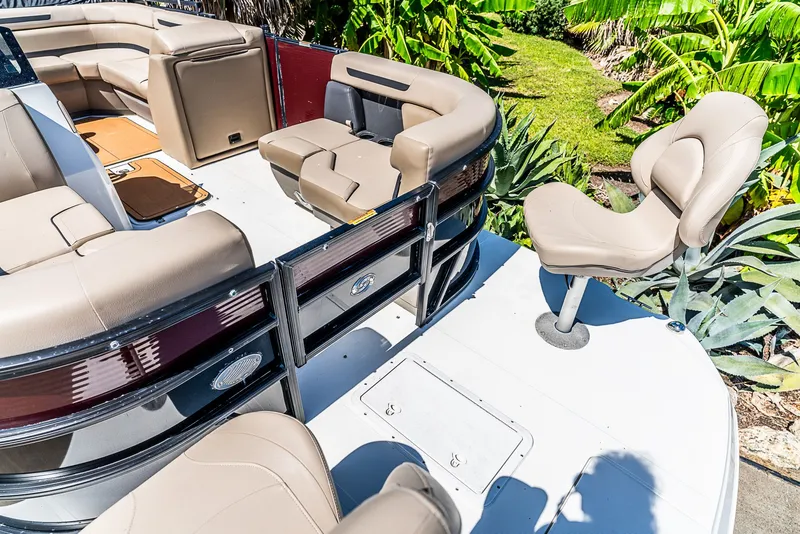 Slide: The Image of A 2022 Hurricane FD2260F pontoon boat with beige seating and lush greenery in the background. - 13