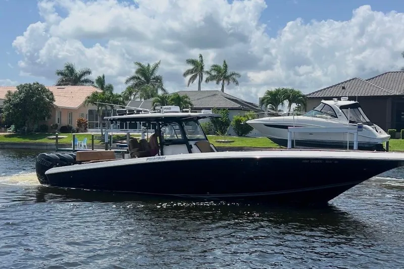 The Image of 2020 Fountain 38 Center Console boat cruising on a sunny day near waterfront homes. - 0