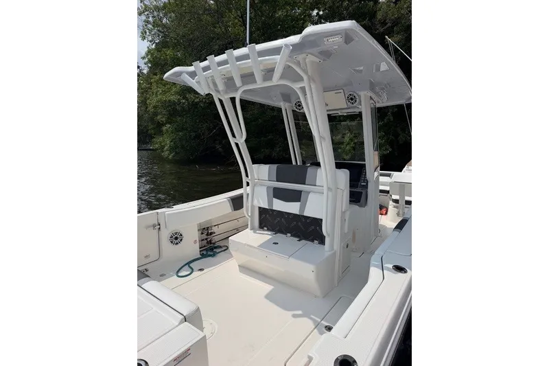 Slide: The Image of 2026 Robalo R270 Center Console boat with T-top and seating, docked near trees. - 9
