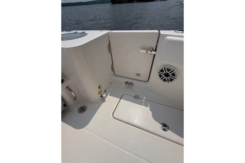 Slide: The Image of 2026 Robalo R270 Center Console boat interior with storage compartment and speaker, near water. - 28