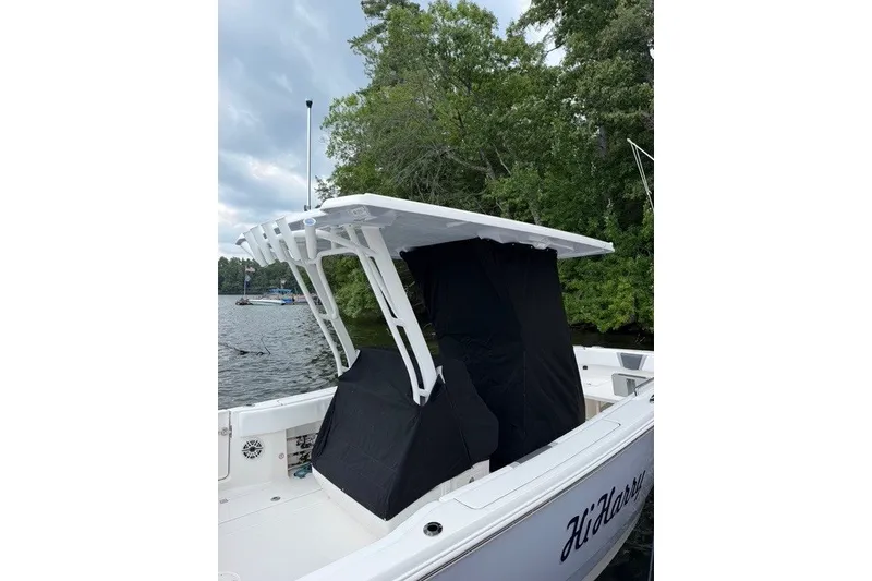 Slide: The Image of 2026 Robalo R270 Center Console boat docked by a lake with lush greenery. - 4