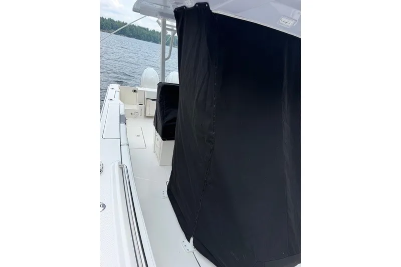 Slide: The Image of 2026 Robalo R270 Center Console boat with black cover on deck, near water. - 7