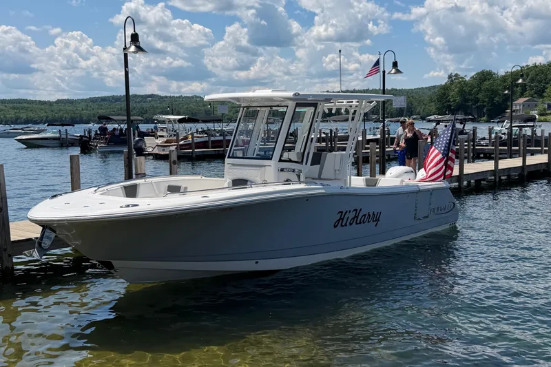 The Image of 2026 Robalo R270 Center Console boat docked on a sunny lake with American flags. - 1