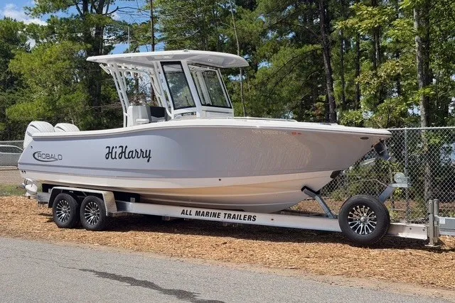 Slide: The Image of 2026 Robalo R270 Center Console boat on trailer, parked outdoors. - 2