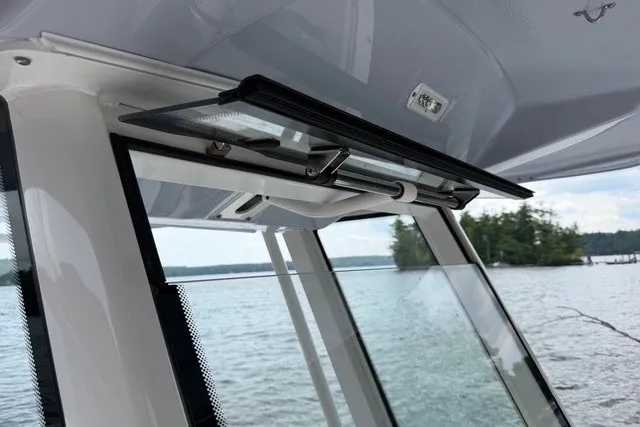 Slide: The Image of 2026 Robalo R270 Center Console boat window overlooking serene lake and trees. - 35