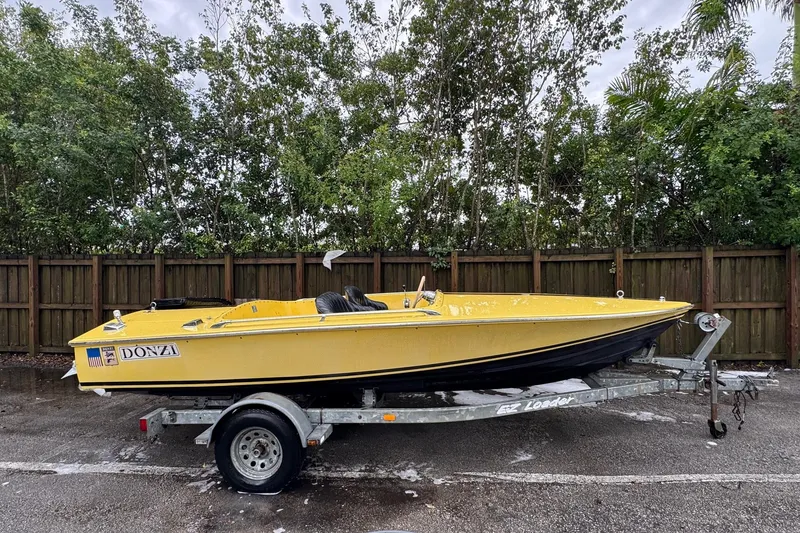 The Image of 1987 Donzi 16 Classic yellow speedboat on trailer, parked outdoors. - 1