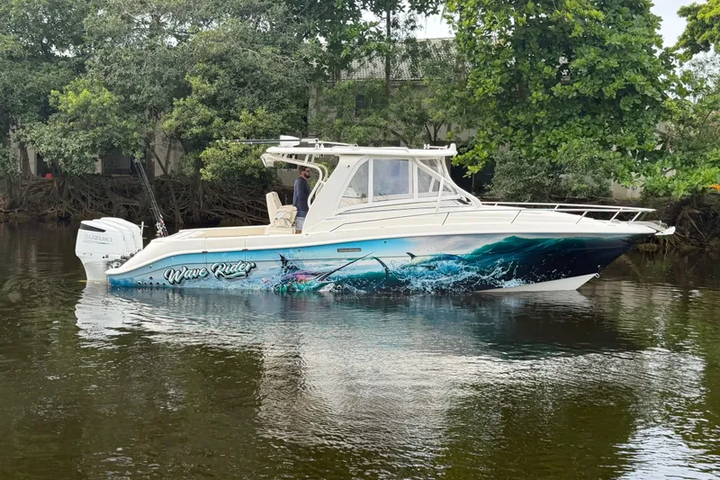 Slide: The Image of 2010 Hydra-Sports 3500 VX boat with vibrant ocean-themed graphics, docked near lush greenery. - 1