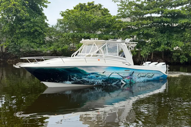 Slide: The Image of 2010 Hydra-Sports 3500 VX boat with vibrant ocean-themed graphics on a calm waterway. - 2
