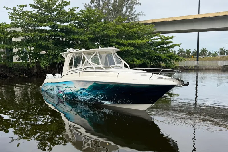 Slide: The Image of 2010 Hydra-Sports 3500 VX boat with custom graphics, docked near lush greenery and a bridge. - 9