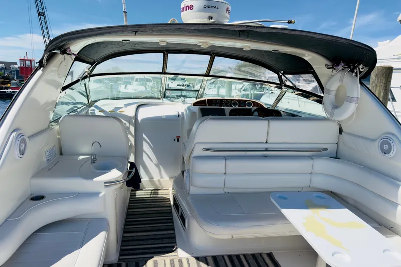Slide: The Image of 1995 Sea Ray Sundancer 370 interior with white seating, table, and helm, docked at marina. - 4