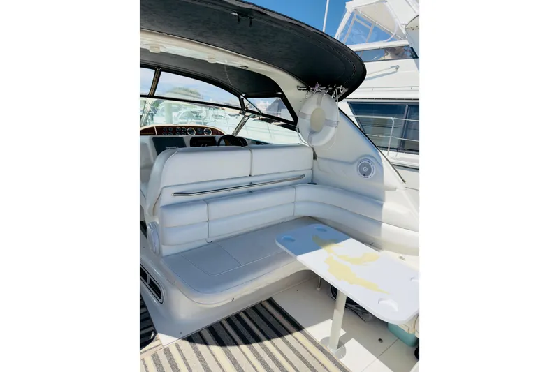 Slide: The Image of 1995 Sea Ray Sundancer 370 interior with white seating and table, under a black canopy. - 7