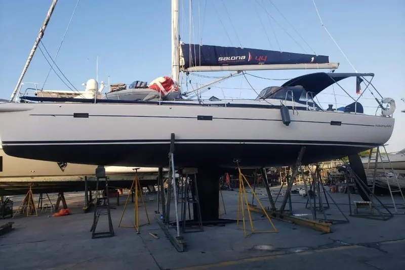 Slide: The Image of 2015 Salona 44 sailboat on dry dock, supported by stands, with visible mast and rigging. - 2
