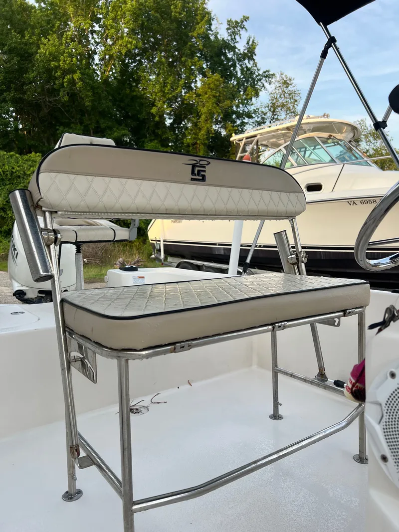Slide: The Image of A white boat seat with metal frame, surrounded by trees and another boat. - 7
