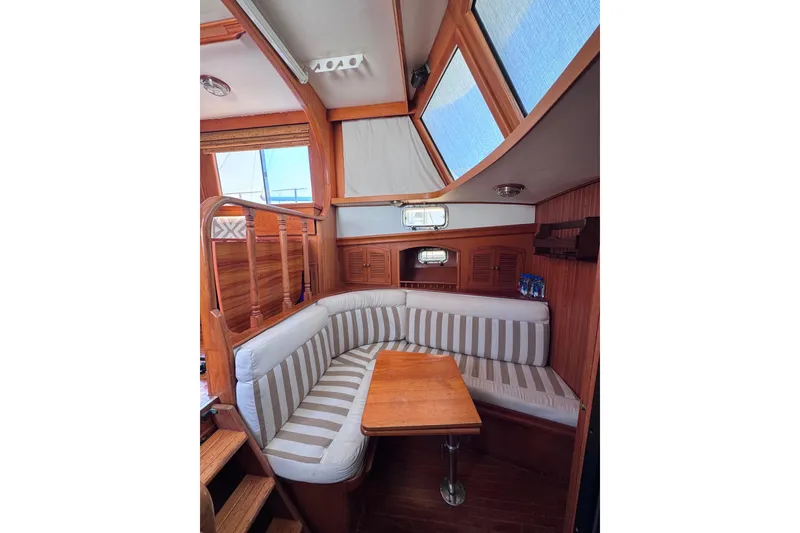 Slide: The Image of Cozy interior of 1987 Fair Weather Mariner 38 sailboat with striped seating and wooden table. - 21