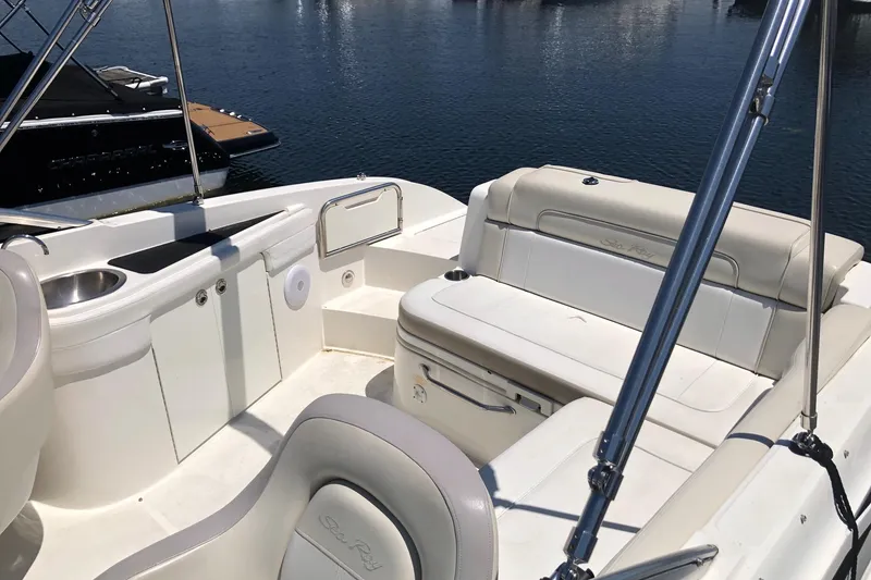 Slide: The Image of 2013 Sea Ray 260 Sundeck interior with seating and sink, docked on calm water. - 5
