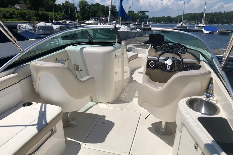 Slide: The Image of 2013 Sea Ray 260 Sundeck interior with helm, seating, and marina view. - 7