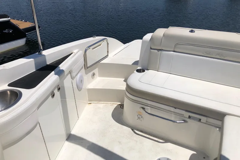 Slide: The Image of 2013 Sea Ray 260 Sundeck interior with seating and sink, docked by the water. - 9
