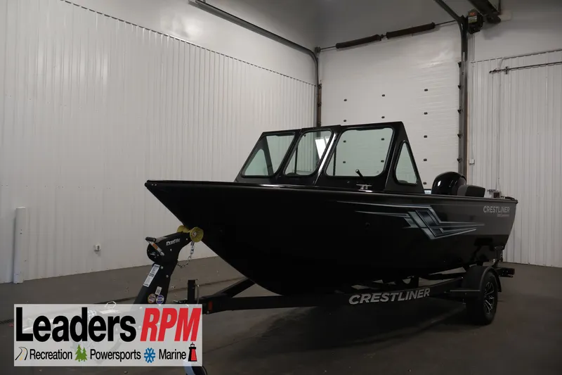 The Image of 2026 Crestliner 1850 Commander boat in showroom, black exterior, on trailer. - 0