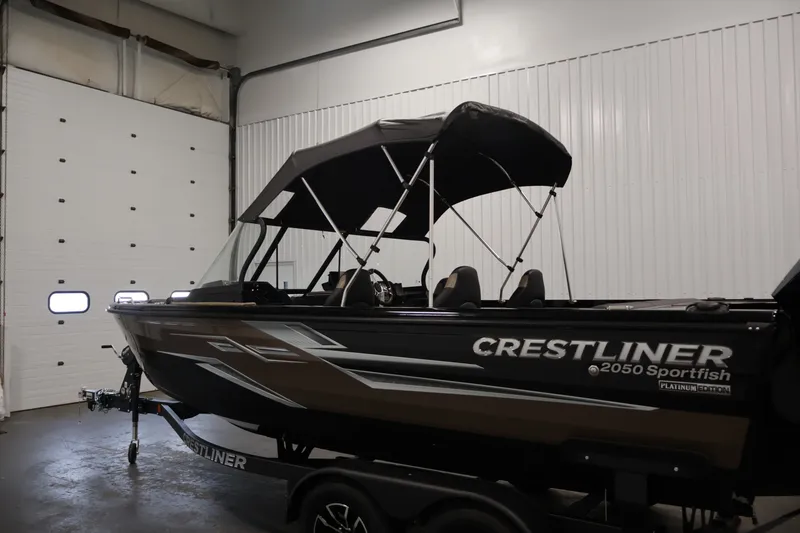 Slide: The Image of 2026 Crestliner 2050 Sportfish boat in a garage, featuring a sleek design and canopy. - 43