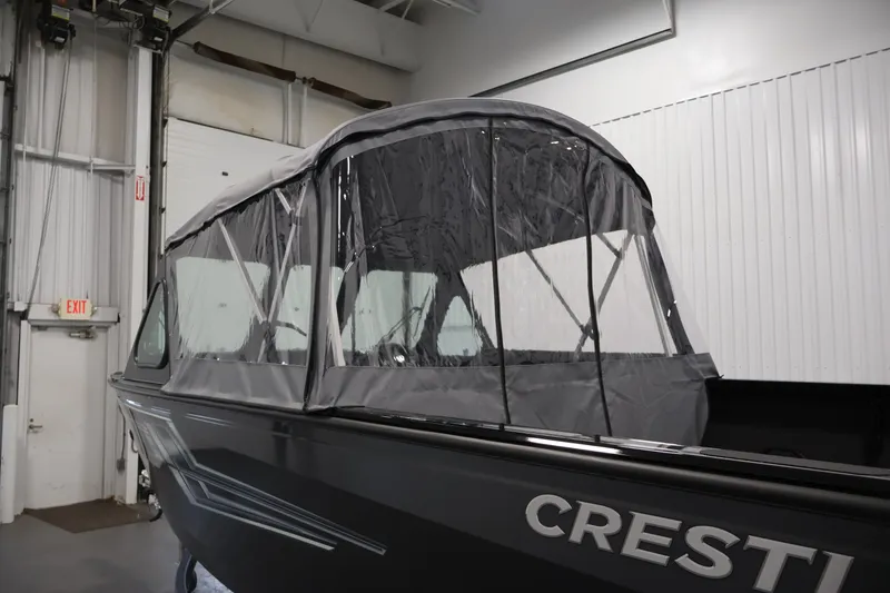 Slide: The Image of 2026 Crestliner 2050 Commander boat with protective canopy in a warehouse setting. - 40