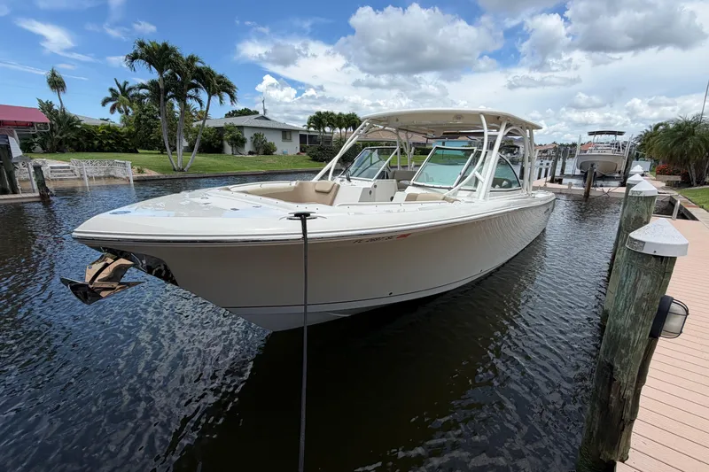 Slide: The Image of 2018 Sailfish 325 DC boat docked in a scenic canal under a partly cloudy sky. - 1