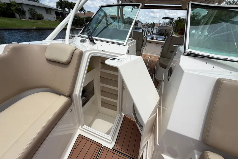 Slide: The Image of 2018 Sailfish 325 DC boat interior with open storage compartment and beige seating. - 11