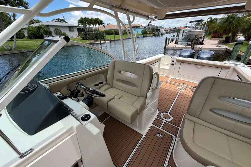 Slide: The Image of 2018 Sailfish 325 DC boat interior with beige seating and wooden deck, docked by a canal. - 14