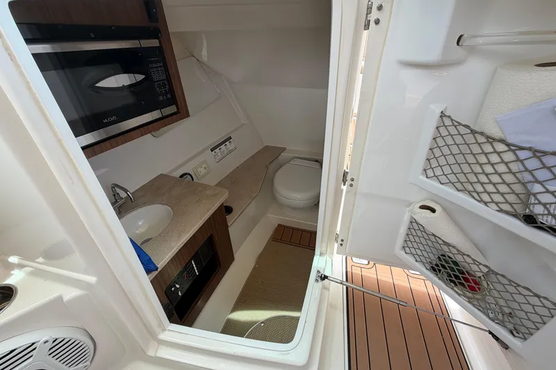 Slide: The Image of Interior of 2018 Sailfish 325 DC boat featuring a compact bathroom and kitchenette. - 24