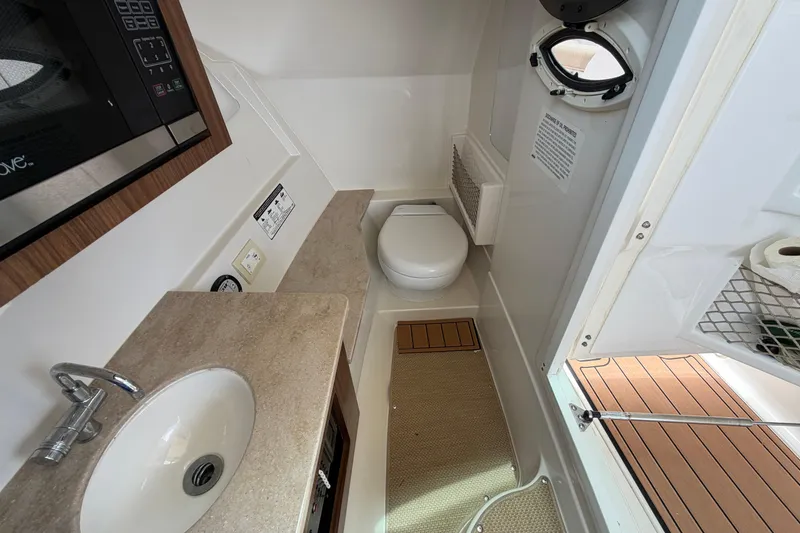Slide: The Image of 2018 Sailfish 325 DC boat interior with sink, toilet, and microwave. - 25