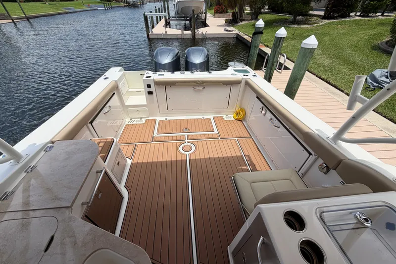 Slide: The Image of 2018 Sailfish 325 DC boat interior with teak flooring and dual engines at dock. - 27