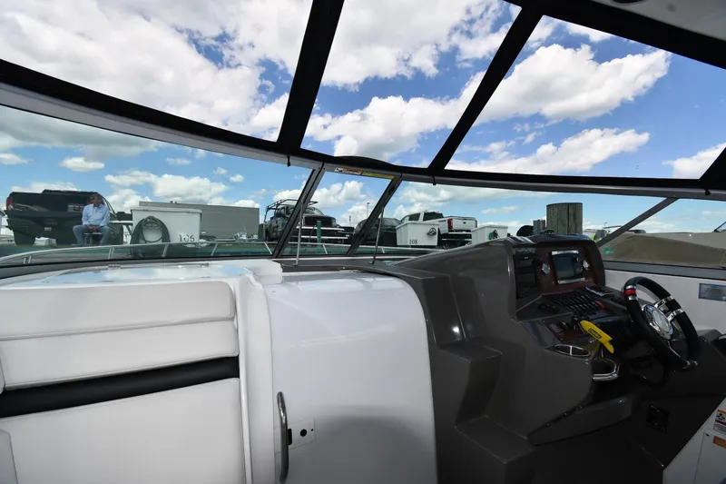 Slide: The Image of 2017 Rinker EX 320 boat interior with dashboard and steering wheel under blue sky. - 12