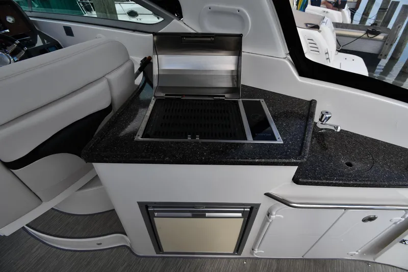 Slide: The Image of 2017 Rinker EX 320 boat interior with kitchenette, grill, and sink. - 18