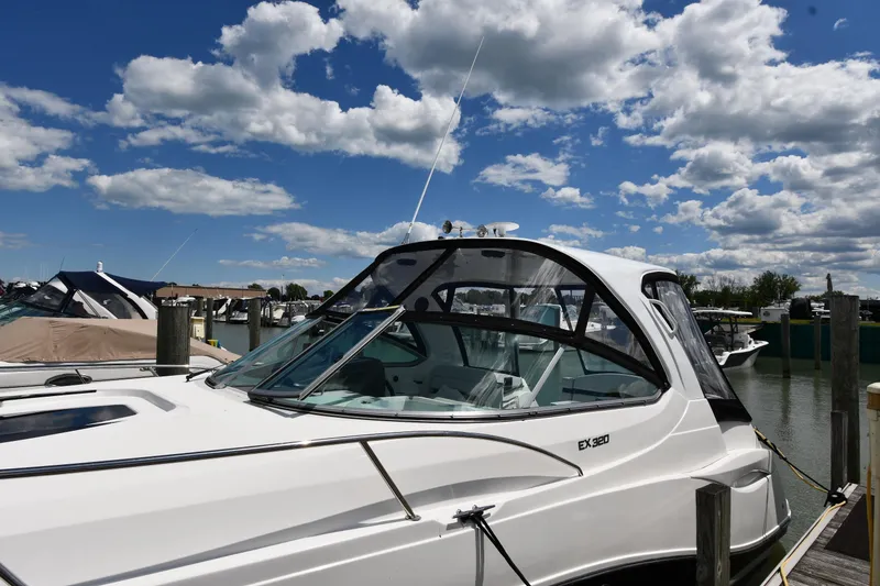 Slide: The Image of 2017 Rinker EX 320 boat docked under a partly cloudy sky. - 2