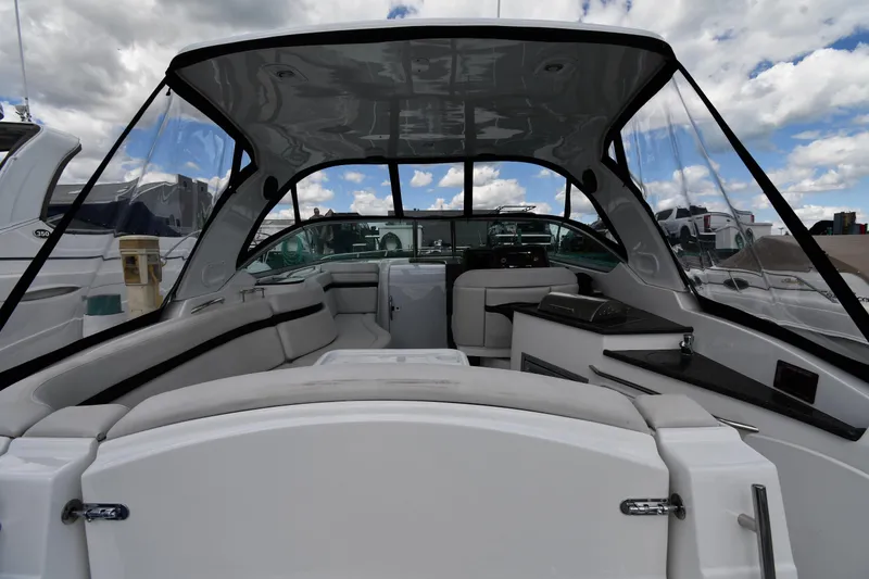 Slide: The Image of 2017 Rinker EX 320 boat interior with seating and canopy under a cloudy sky. - 23