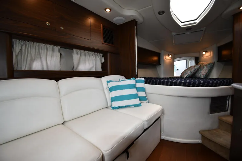 Slide: The Image of Luxurious interior of 2017 Rinker EX 320 boat with white seating and striped cushions. - 27
