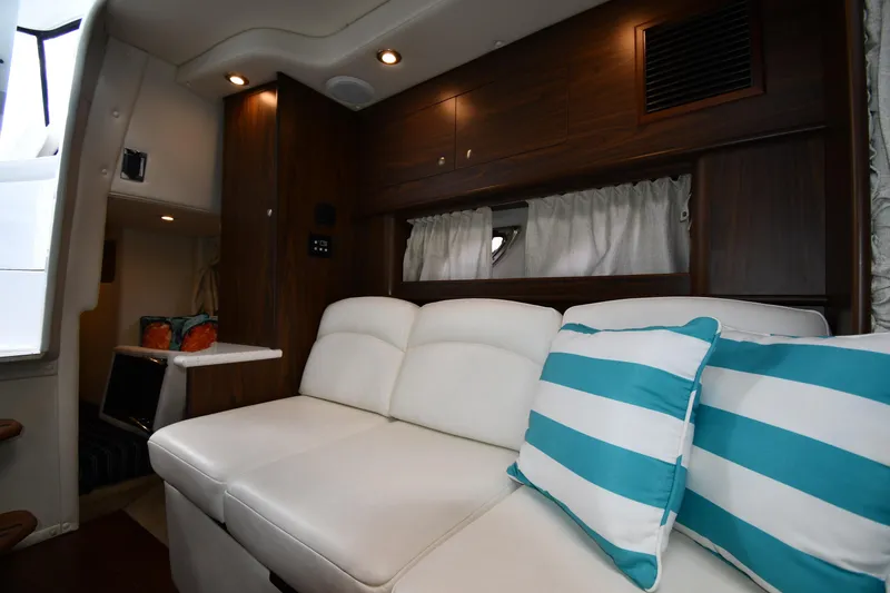 Slide: The Image of 2017 Rinker EX 320 interior with white seating and striped cushions. - 29