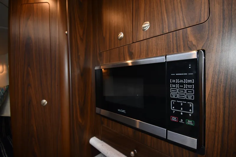Slide: The Image of Microwave in 2017 Rinker EX 320 boat with wood-paneled interior. - 31
