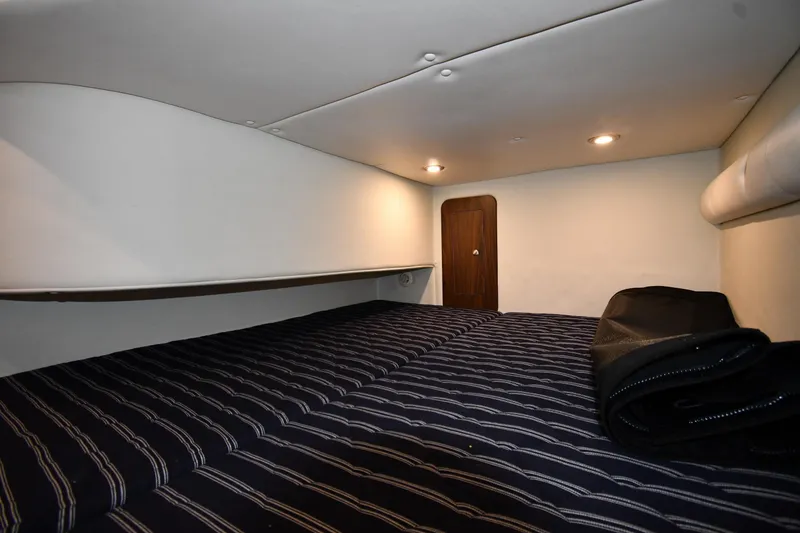 Slide: The Image of 2017 Rinker EX 320 cabin interior with striped bedding and ambient lighting. - 36