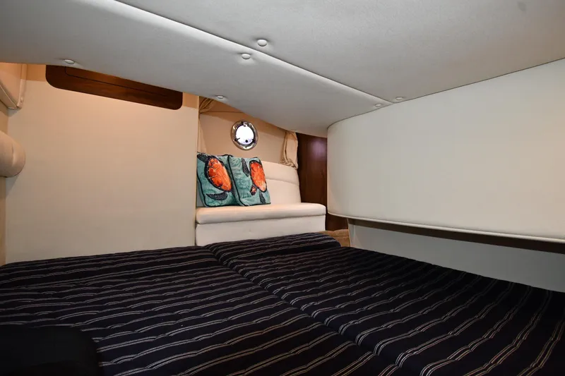 Slide: The Image of 2017 Rinker EX 320 cabin interior with striped bedding and decorative pillows. - 37