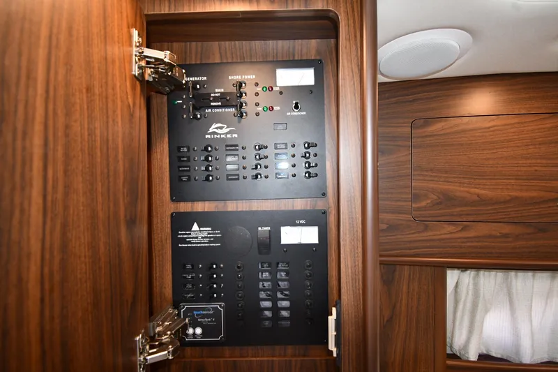 Slide: The Image of Electrical control panel inside 2017 Rinker EX 320 boat, featuring wood finish and various switches. - 38