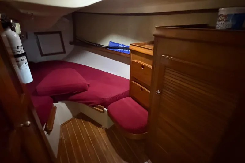 Slide: The Image of Cozy cabin interior of 1990 Island Packet 38 sailboat with red cushions and wooden cabinetry. - 10
