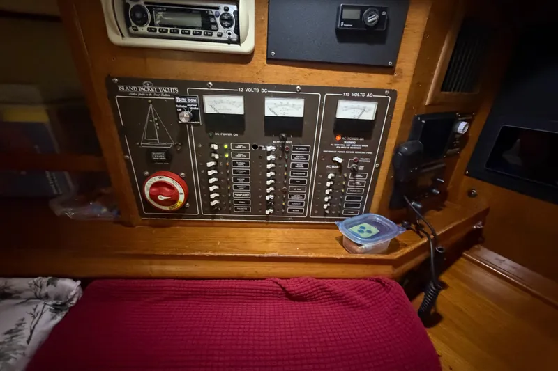 Slide: The Image of Electrical control panel of a 1990 Island Packet 38 yacht, featuring various switches and meters. - 13