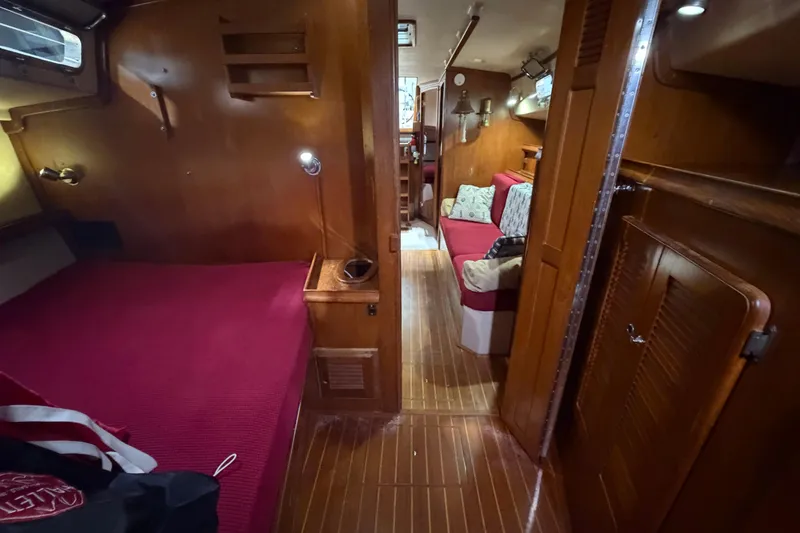 Slide: The Image of Interior of 1990 Island Packet 38 sailboat with cozy wooden furnishings and red bedding. - 16